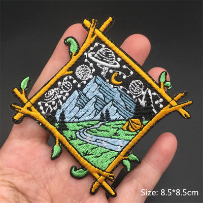 Embroidered patch with nature design held in a hand on a dark background