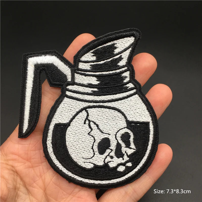 Embroidered patch of a skull design held in a hand with a dark background