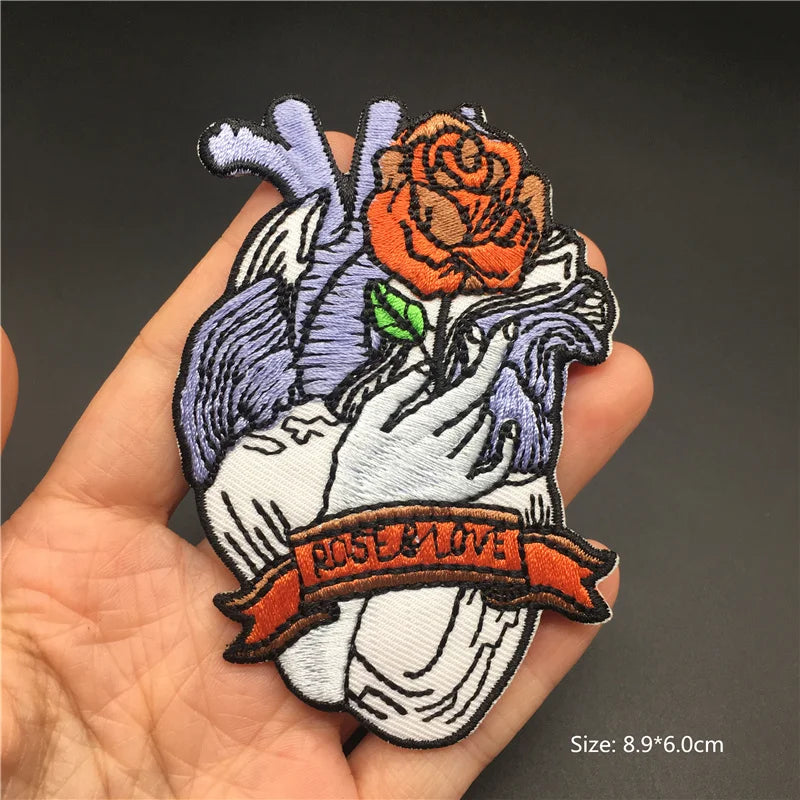 Embroidered patch with a hand holding a rose and 'Rose & Love' banner on a dark background.