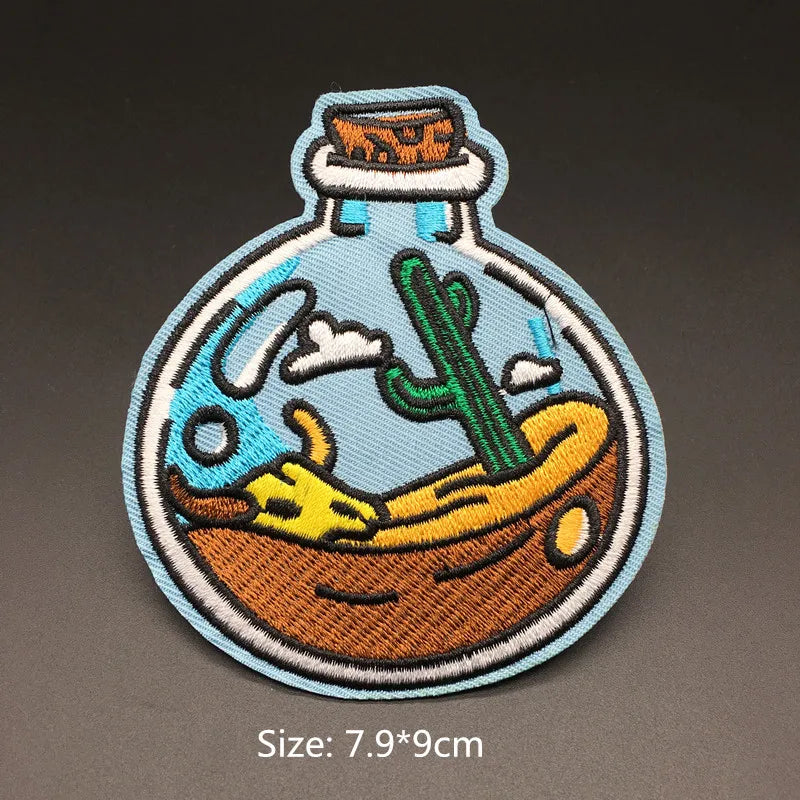 Bottle-shaped embroidered desert landscape iron-on patch with cactus skull and clouds approximately 7.9x9cm on a dark background