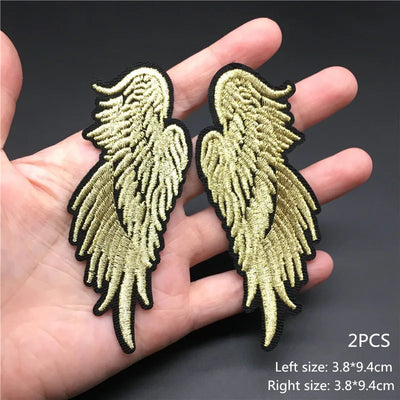 Gold angel wings patch held in a hand with size information on a dark background