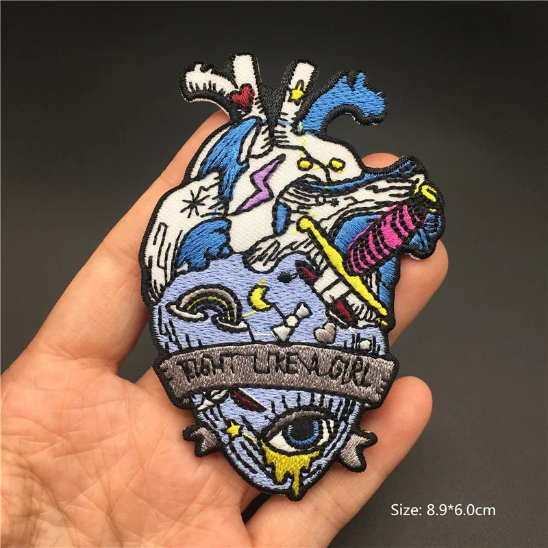 Colorful embroidered patch with intricate designs held in a hand against a dark background