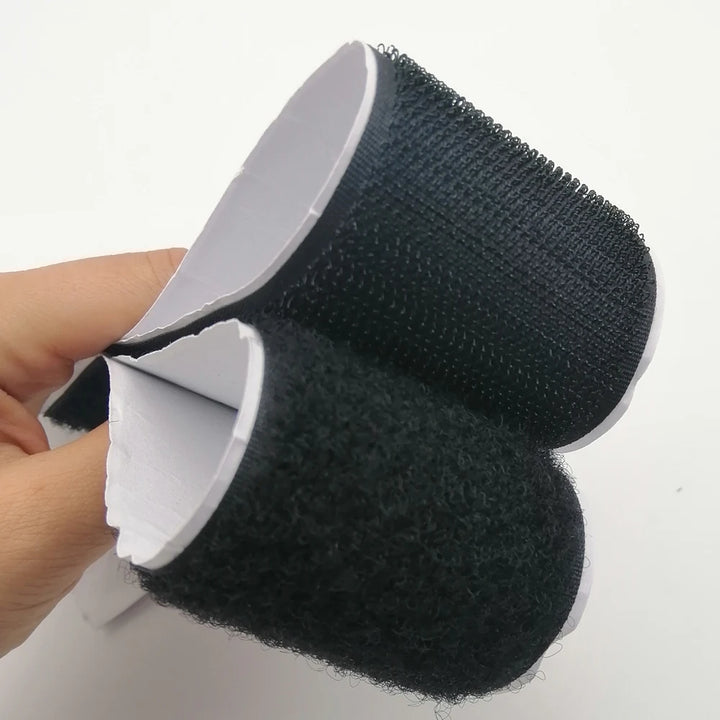Black Velcro strips  hook and loop held by a hand on a white background