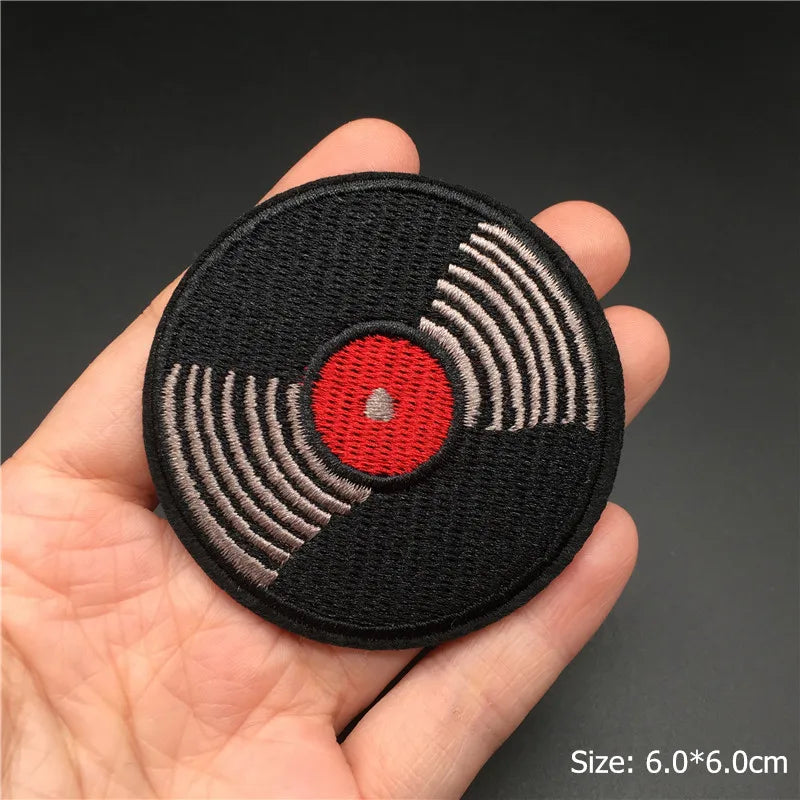 Record player patch held in a hand with a dark background