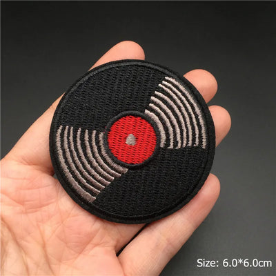 Record player patch held in a hand with a dark background