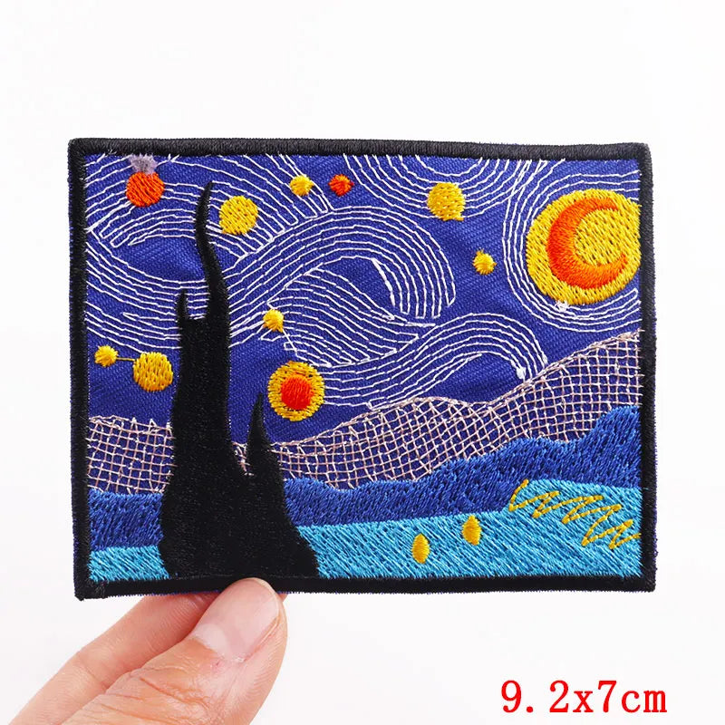 Embroidered patch with a starry night design held by a hand, on a white background.