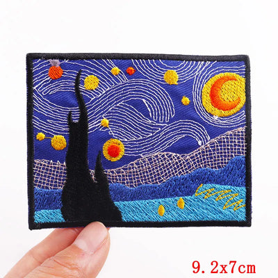 Embroidered patch with a starry night design held by a hand, on a white background.