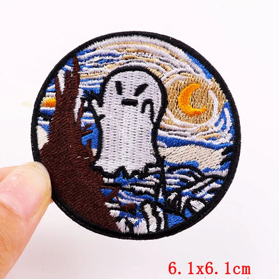 Embroidered patch of a ghost under a crescent moon with a hand holding it, on a white background.