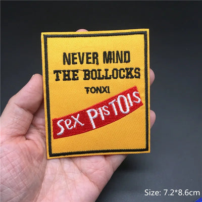 Embroidered patch with text held in a hand against a dark background