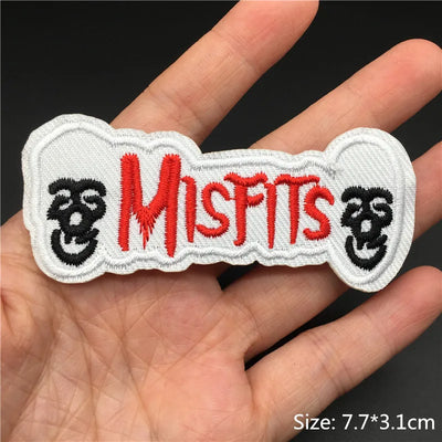 Embroidered patch with 'Misfits' text held in a hand against a dark background