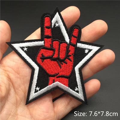 Embroidered patch with a red hand and black star design held in a hand.