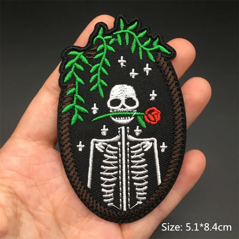 Embroidered patch with a skeleton design held in a hand against a dark background