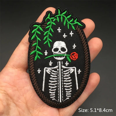Embroidered patch with a skeleton design held in a hand against a dark background