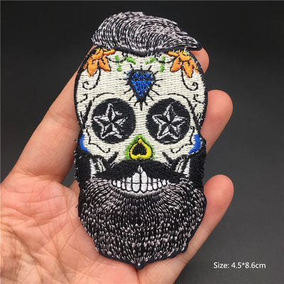Embroidered skull patch held in a hand with a dark background