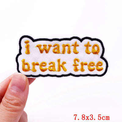 Embroidered patch with 'i want to break free' text held by a hand on a white background