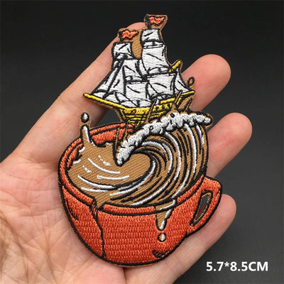 Embroidered patch of a ship on a wave held in a hand with a dark background
