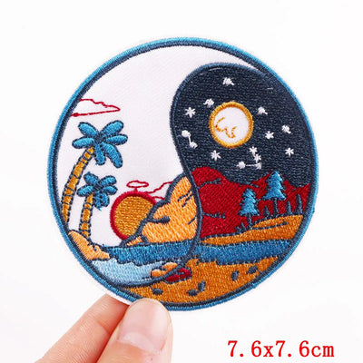 Circular embroidered patch with desert and palm tree design held by a hand, on a white background.