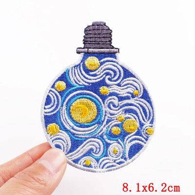 Embroidered patch with starry night design held by a hand on a white background