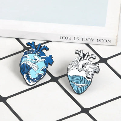 Heart-shaped enamel pins in blue and white design on a checkered surface