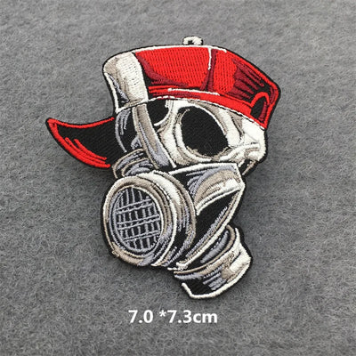 Embroidered patch of a character wearing a gas mask and red cap on a gray background.
