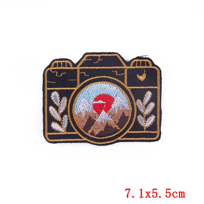 Camera-shaped patch with embroidered design on a white background