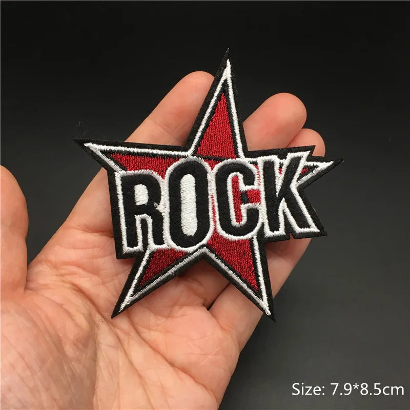 Star-shaped patch with 'ROCK' text held in a hand against a dark background