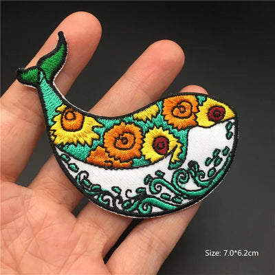 Colorful embroidered fish patch held in a hand with a dark background