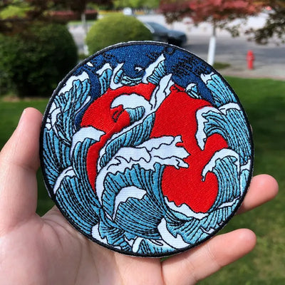 Circular patch with red center and blue waves held in a hand, outdoor background