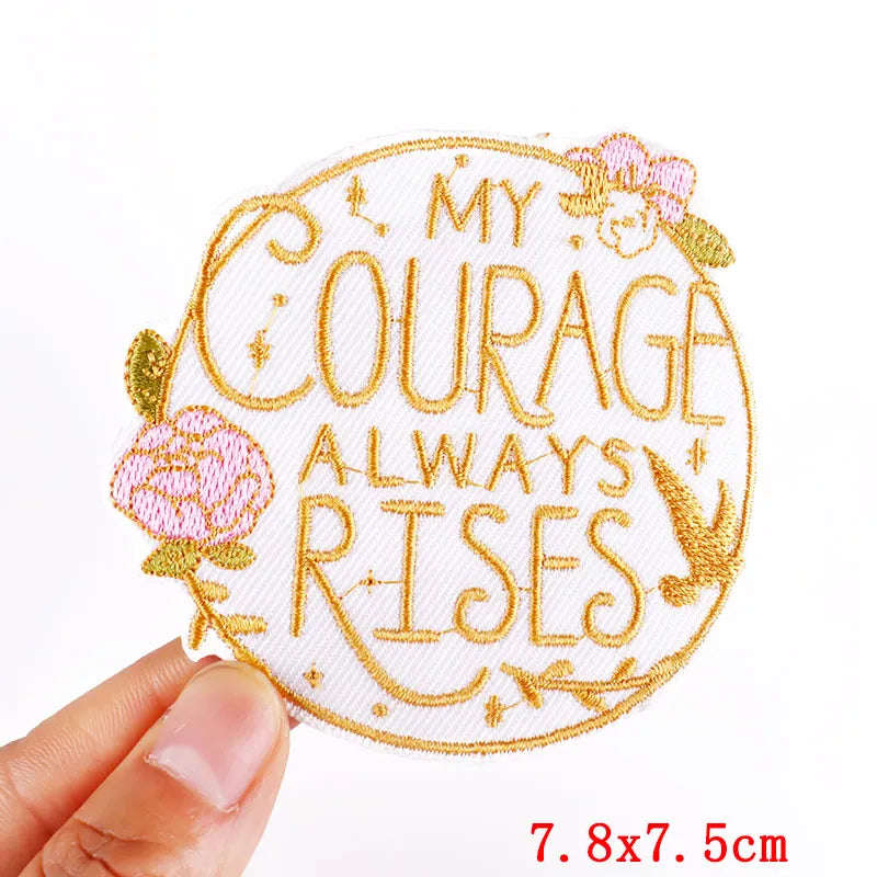 Embroidered patch with 'My Courage Always Rises' text held by a hand on a white background