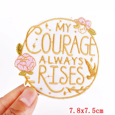 Embroidered patch with 'My Courage Always Rises' text held by a hand on a white background