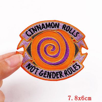 Patch with orange and purple spiral design and text held by a hand on a white background