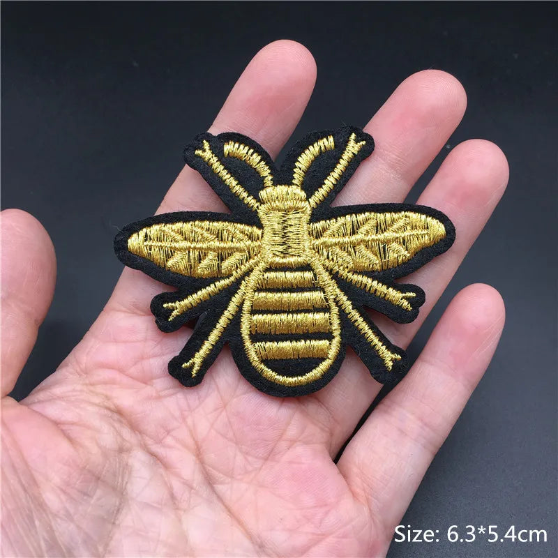 Gold and black bee patch held in a hand with a dark background