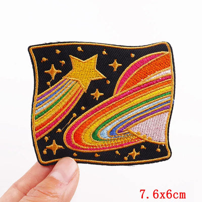 Embroidered patch with rainbow and star design held by a hand on a white background