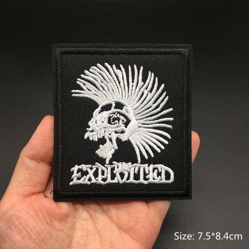 Black patch with white skull design held in a hand against a dark background
