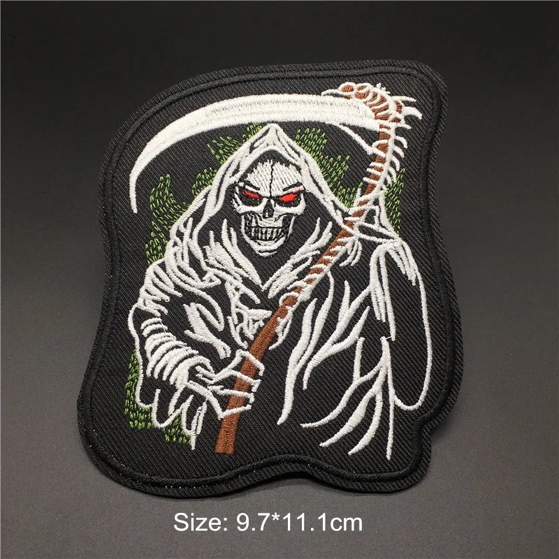 Embroidered patch of a skeleton with red eyes and a scythe on a dark background