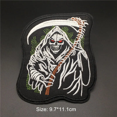 Embroidered patch of a skeleton with red eyes and a scythe on a dark background