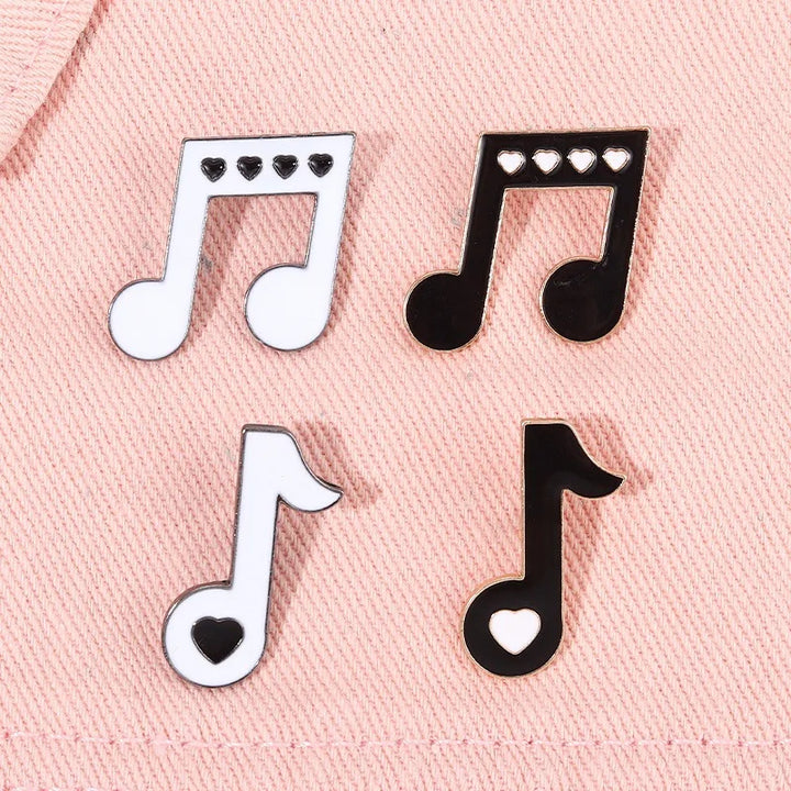 Music note enamel pins on a pink fabric background