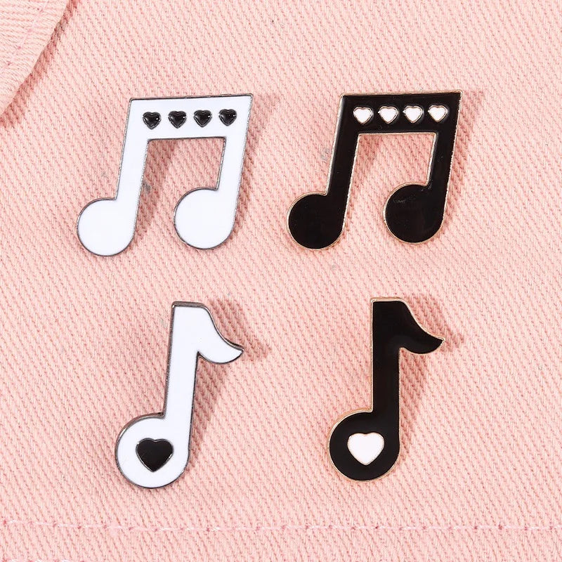 Music note enamel pins on a pink fabric background
