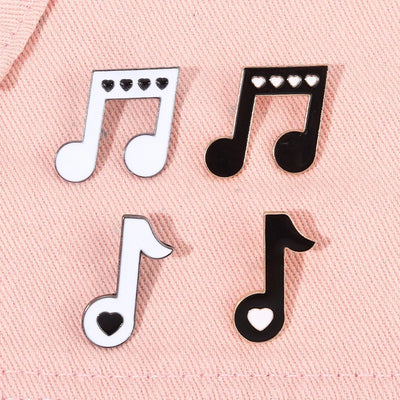 Music note enamel pins on a pink fabric background