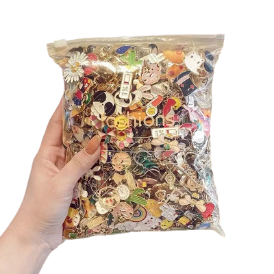 Hand holding a clear bag filled with various colorful pins against a white background
