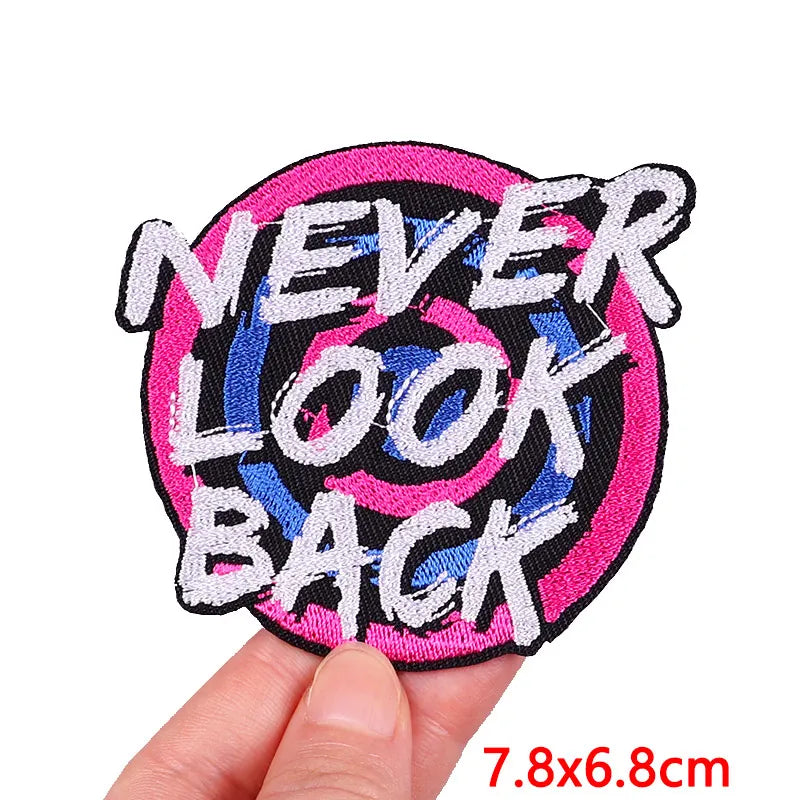 Embroidered patch with 'NEVER LOOK BACK' text held by a hand on a white background