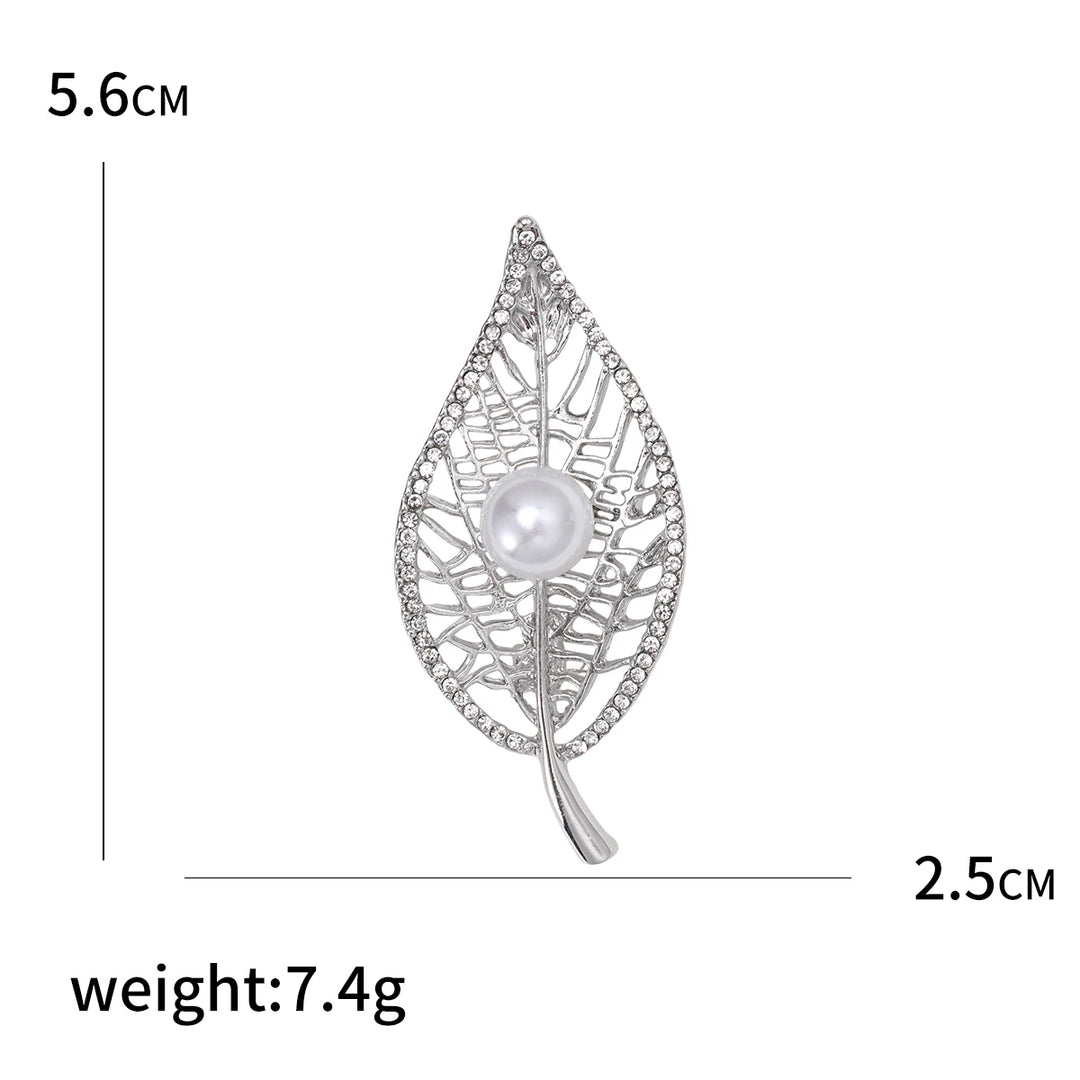 Silver leaf-shaped brooch with pearl center and measurements on a white background