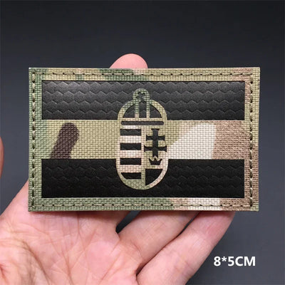 Camouflage patch with emblem held in a hand against a dark background