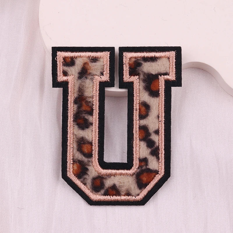 Leopard print letter 'U' patch on a light pink background