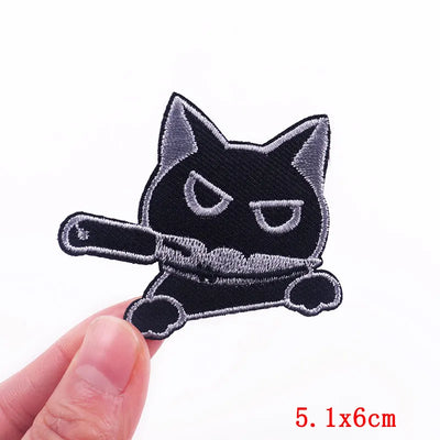 Black and white cat-shaped patch held by a hand with measurement label '5.1x6cm'.