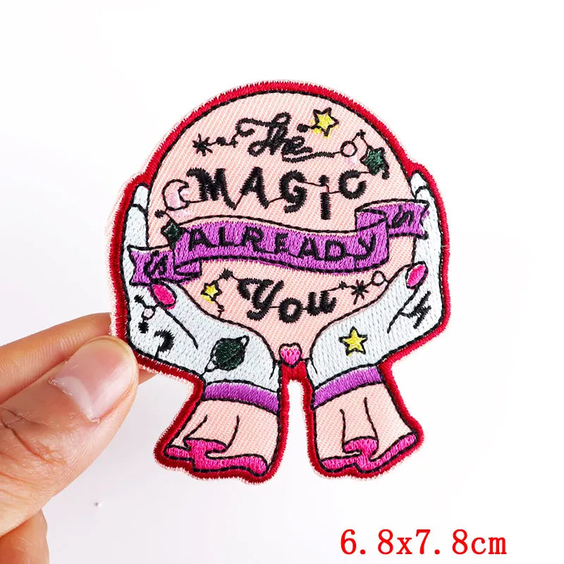 Embroidered patch with text and design held by a hand, on a white background
