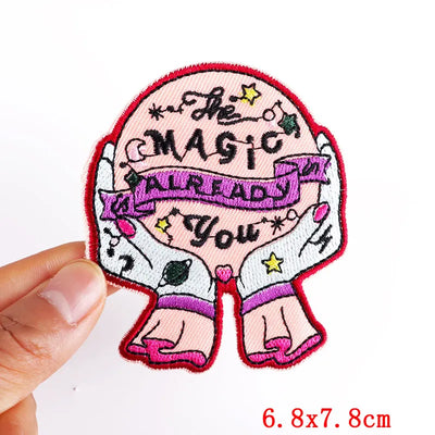Embroidered patch with text and design held by a hand, on a white background
