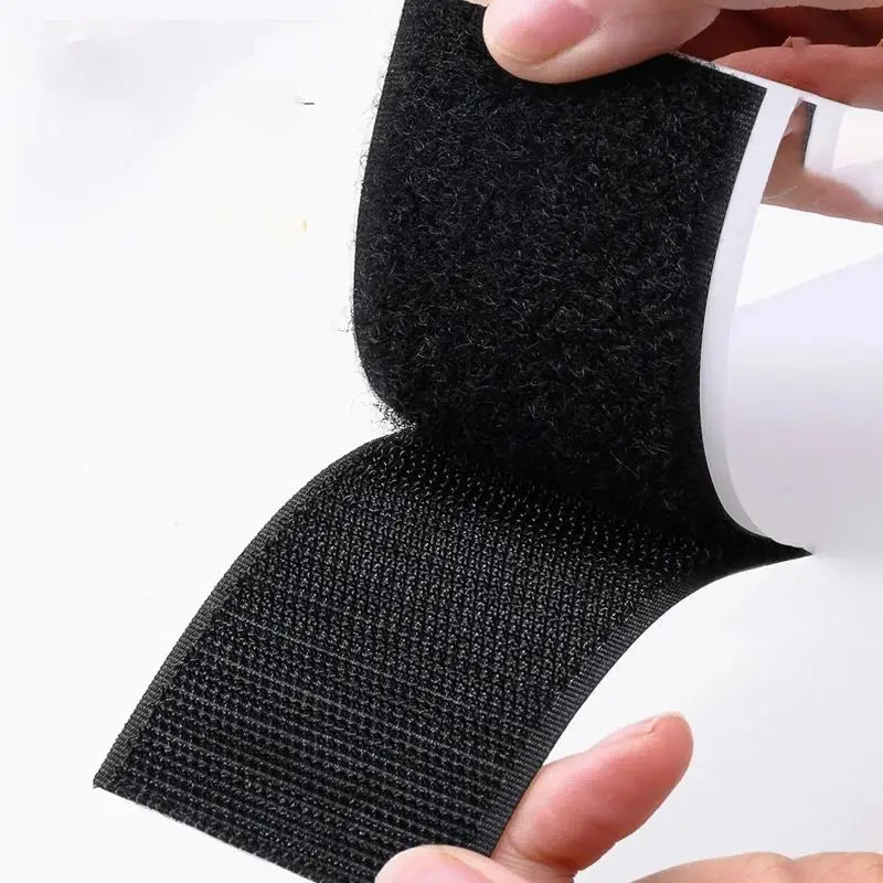 Black velcro strip held by a hand on a white background