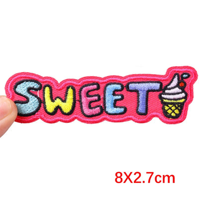 Embroidered patch with 'SWEET' text and ice cream icon, held by a hand on a white background.