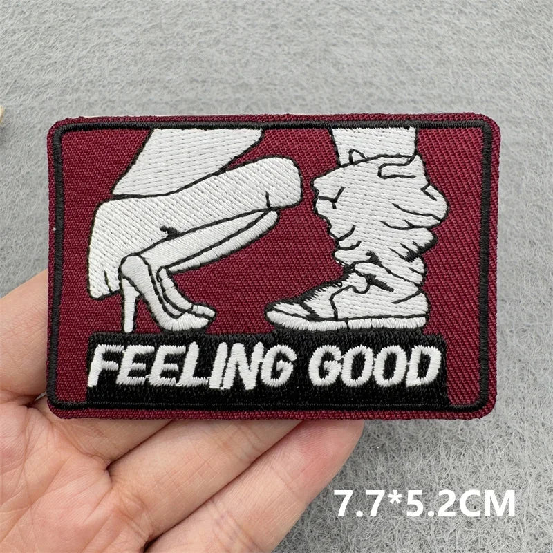 Patch with a graphic of feet and text 'FEELING GOOD' held in hand against gray background